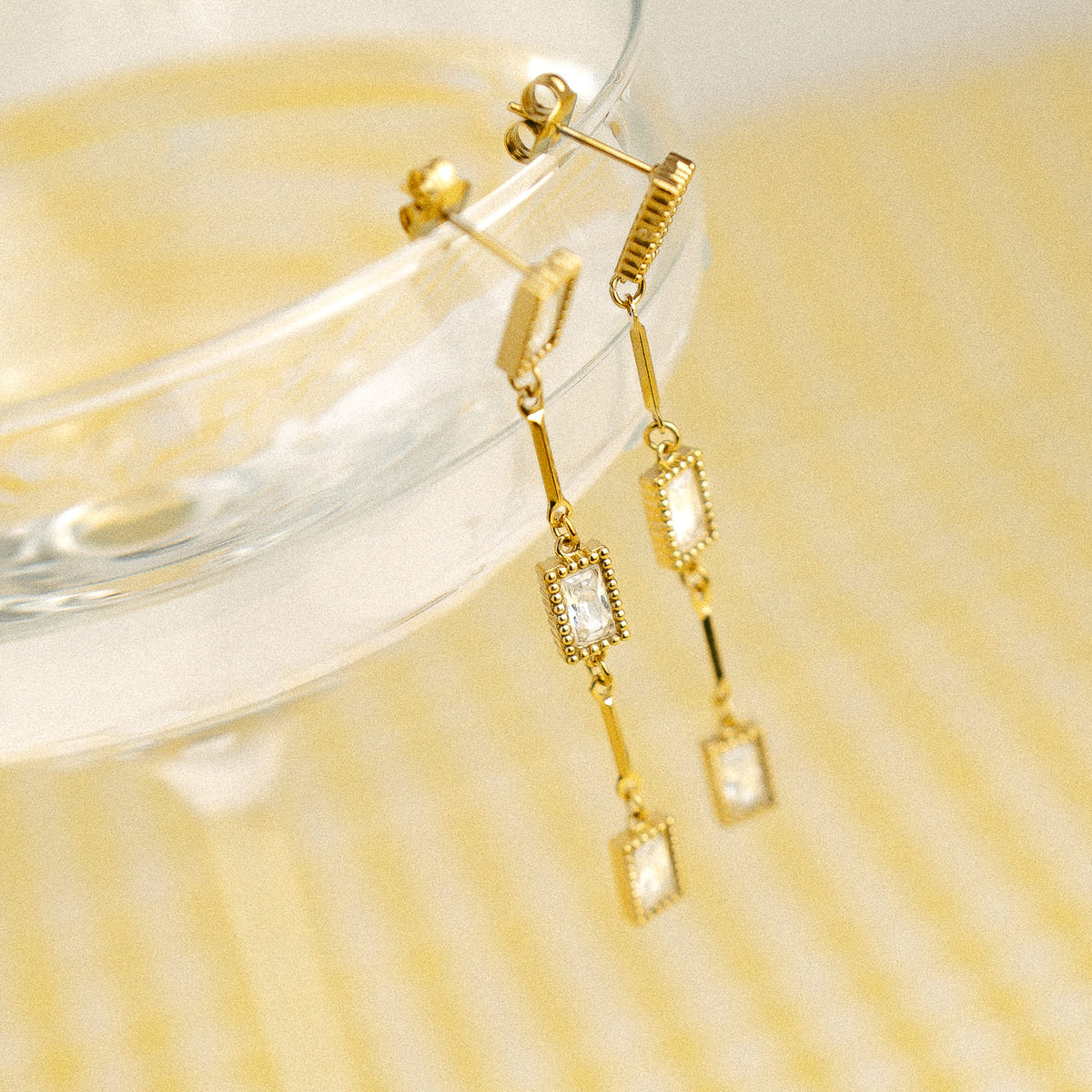 Boucles pendantes dorées à zircons posées sur un verre