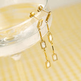Boucles pendantes dorées à zircons posées sur un verre
