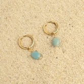 Paire de mini créoles en plaqué or à amazonite posées sur le sable