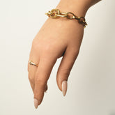 Main portant une bague martelée dorée et un bracelet chaîne