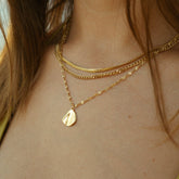 Collier triple rang doré à pendentif coquillage porté au cou