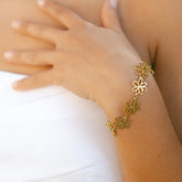 Bracelet à maillons fleurs dorés porté au poignet