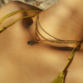 Collier triple rang doré porté sur une épaule bronzée
