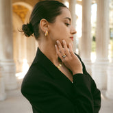 Femme en veste noire portant des bijoux dorés et une bague bicolore