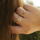 Main portant des bagues dorées à zircon vert et motif fleuri