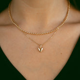 Collier chaîne jaseron et collier à pendentif cœur dorés portés au cou