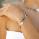 Bracelet à maillons fleurs argentés porté au poignet