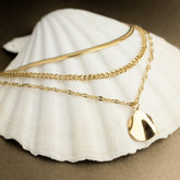 Collier triple rang doré posé sur un coquillage