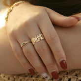 Main portant une bague fleurie dorée et une bague fine