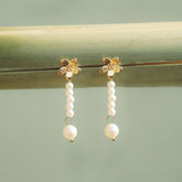 Paire de boucles fleur dorées à cascade de perles posées sur une rambarde