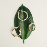 Créoles et bague striées en plaqué or posées sur une feuille verte