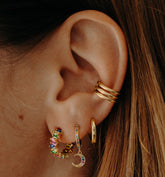 Mini créoles en plaqué or multicolores à pendentif lune portées avec un earcuff