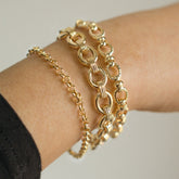 Bracelets chaînes dorées à grosses mailles superposés au poignet