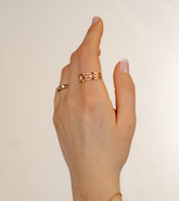 Main portant une bague triple rang dorée sertie de zircons