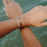 Bracelets dorés superposés portés aux poignets au bord de l&