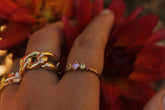 Bague en plaqué or à zircons roses et verts portée avec une autre bague dorée